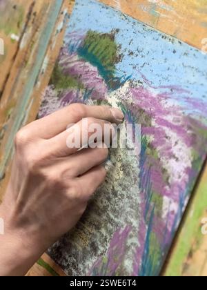 Dessiner avec des pastels gros plan. Femme dessinant de belles fleurs de crocus avec pastel doux à table. Banque D'Images