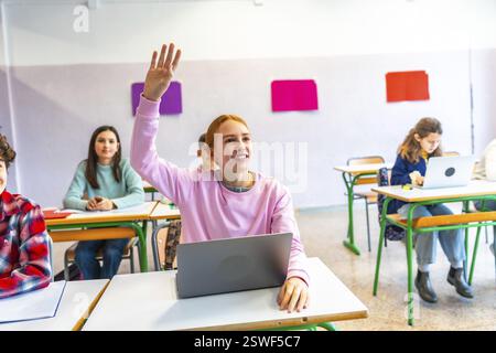 Smart Student lève la main pour poser une question en classe, montrant son engagement et sa participation à l’éducation moderne Banque D'Images