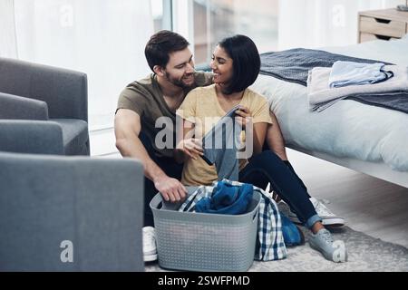 Lessive, plier et couple heureux avec des vêtements dans le panier pour le nettoyage, la routine de corvée et l'hygiène à la maison. Mariage, relation et homme et femme avec Banque D'Images