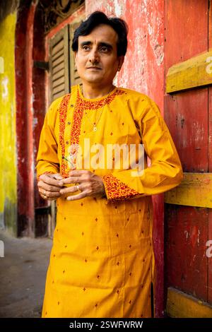 Un indien portant un dhoti rouge bengali traditionnel indien et kurta orange posant en plein air dans les rues de kolkata Banque D'Images