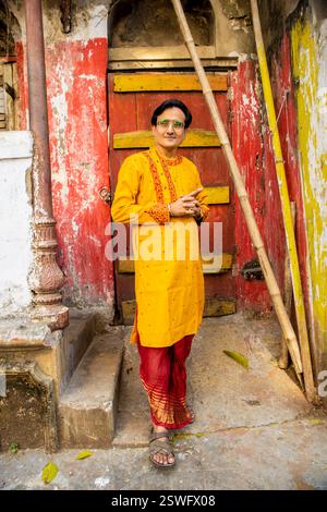 Un indien portant un dhoti rouge bengali traditionnel indien et kurta orange posant en plein air dans les rues de kolkata Banque D'Images