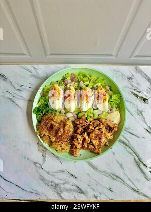 Un saladier vibrant et nutritif composé de poulet grillé, d'œufs durs épicés et de légumes verts frais, parfait pour un repas sain et une photographie culinaire Banque D'Images