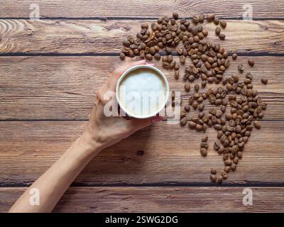 Café dans une tasse de papier est sur la table brune. Banque D'Images