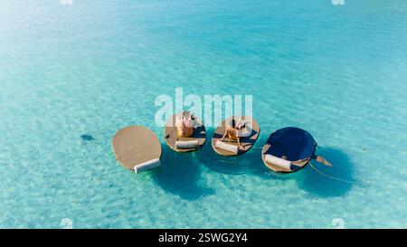 Moments de détente sur des chaises longues flottantes dans les eaux turquoises de Koh Kood, Thaïlande Banque D'Images