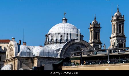 Une vue panoramique sur un bâtiment historique avec un grand dôme et deux hautes tours contre un ciel bleu clair. L'architecture présente des détails complexes Banque D'Images