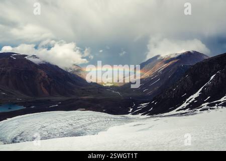 Arc-en-ciel au-dessus d'une vallée de montagne. Paysage sombre avec arc-en-ciel lumineux au-dessus du glacier dans la vallée de montagne. Vue de dessus à Rainbo coloré Banque D'Images