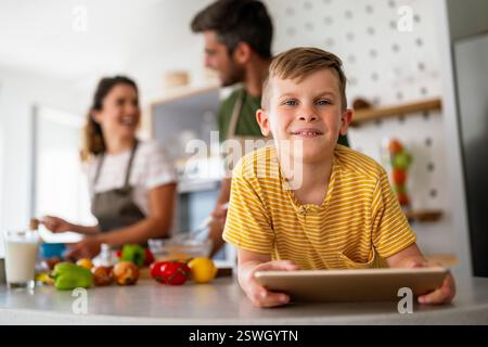 Famille heureuse avec enfant s'amusant en utilisant la tablette ensemble, les parents et l'enfant riant se relaxant à la maison Banque D'Images
