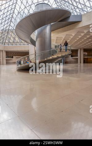 Paris, France - 02 23 2022 : Musée du Louvre. Le grand escalier en colimaçon et l'ascenseur sous la pyramide du Louvre dans le hall de réception Banque D'Images