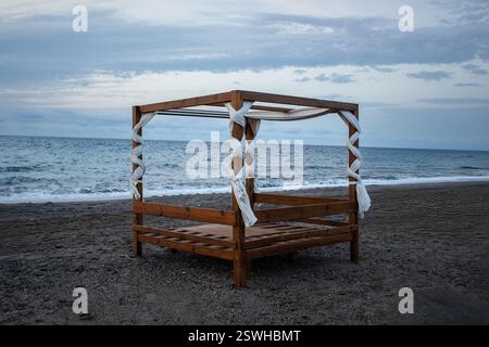 Gazebo en bois sur la plage au bord de la mer au coucher du soleil. Banque D'Images
