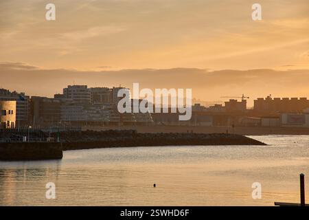 Cette photo capture un coucher de soleil tranquille sur la plage de San Lorenzo à Gijon, Espagne. L'image montre la descente du soleil, projetant une lueur chaude et dorée Banque D'Images