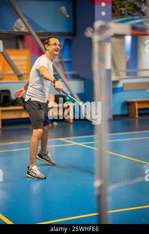 Homme jouant au badminton dans des vêtements de sport sur un terrain d'intérieur Banque D'Images