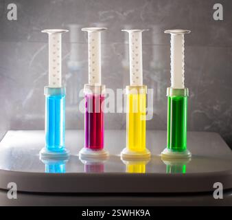 Un ensemble de seringues multicolores avec différents parfums sur la cuvette des toilettes pour le nettoyage et la désinfection. Hygiène et effet antibactérien Banque D'Images