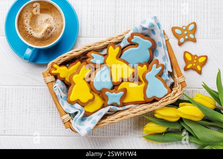 Scène de Pâques avec biscuits au pain d'épice en forme de lapin, tulipes jaunes et tasse à café Banque D'Images