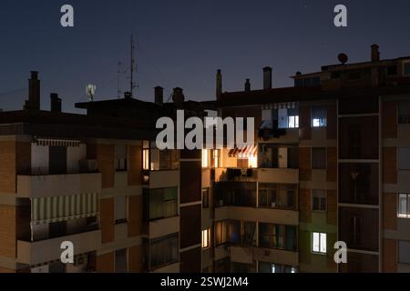 Vue de deux façades reliées en angles d'un immeuble urbain. La nuit est sombre et certaines des maisons sont éclairées à la lumière électrique. Concept de en Banque D'Images