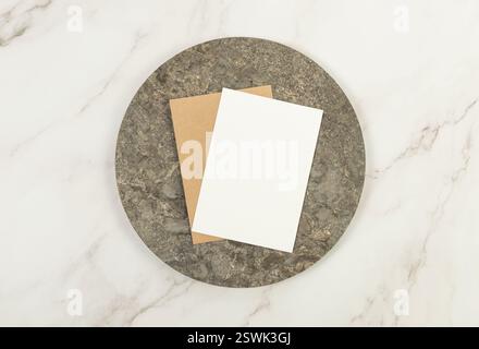 Vue de dessus de la plaque de marbre brun, cartes blanches et brunes sur fond de marbre blanc. Présentation des aliments, plateau en pierre. Espace de copie, pose à plat. Banque D'Images