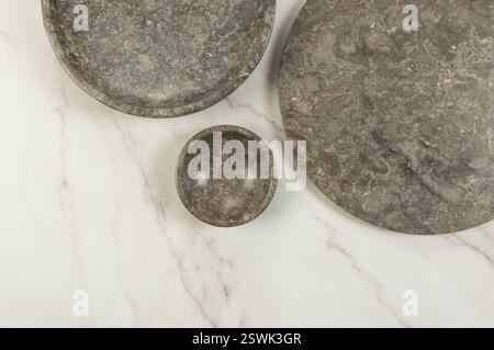 Vue de dessus du plateau en marbre brun, de l'assiette et du bol sur fond de marbre blanc. Présentation des aliments, plats, plateau en pierre. Espace de copie, pose à plat. Banque D'Images