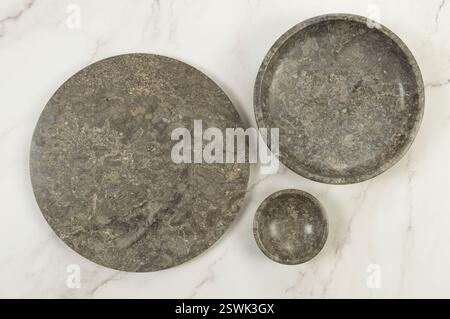 Vue de dessus du plateau en marbre brun, de l'assiette et du bol sur fond de marbre blanc. Présentation des aliments, plats, plateau en pierre. Espace de copie, pose à plat. Banque D'Images