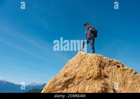 Homme debout au sommet d'un rocher, montagne, regardant la vue. Banque D'Images