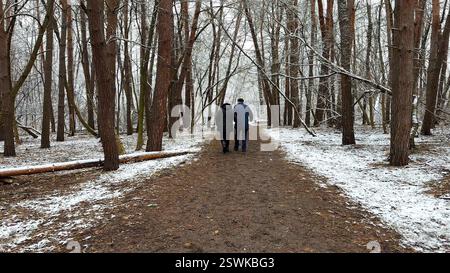Couple mûr allant sur le chemin enneigé à la forêt de pins d'hiver. Mari senior et femme marchant à travers le sentier dans la forêt de conifères. Ancienne paire de Banque D'Images