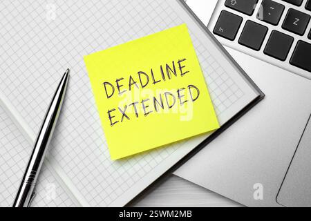 Note papier avec texte Deadline Extended, cahier, stylo et ordinateur portable sur table, vue de dessus Banque D'Images