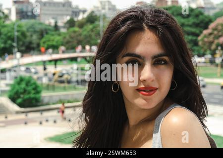 Jeune femme brune avec rouge à lèvres rouge posant dans un parc urbain à buenos aires, argentine Banque D'Images