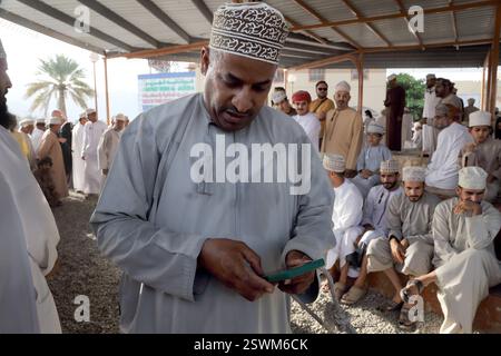 Homme omanais utilisant un smartphone au marché de bétail de Nizwa Nizwa Oman Banque D'Images