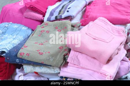 Pile de vêtements de bébé en couleurs rose et postel. Nettoyage et recyclage. Écologie et upcycle. Banque D'Images