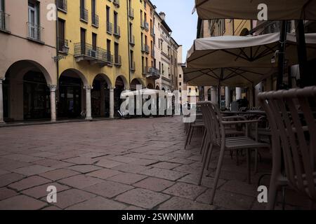 Mantova, Italie - 17 FÉVRIER 2025 - place avec tables et chaises de restaurants bordées par des porches par un jour nuageux Banque D'Images