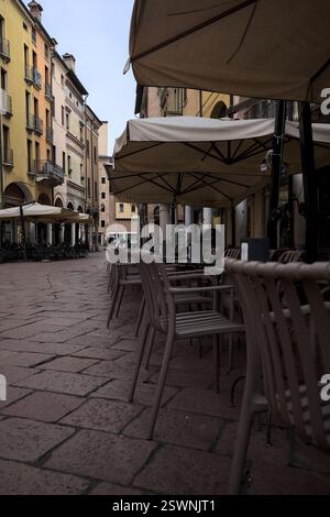 Mantova, Italie - 17 FÉVRIER 2025 - place avec tables et chaises de restaurants bordées par des porches par un jour nuageux Banque D'Images