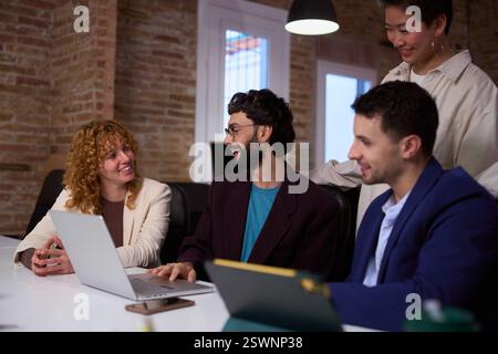 Équipe de démarrage discutant du projet sur ordinateur portable dans le bureau moderne Banque D'Images