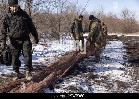 Marioupol, Ukraine. 22 février 2025. Camouflage d'un char T64 par l'équipage de la 56e brigade d'infanterie motorisée séparée de Marioupol en position fermée près du front dans la région de Donetsk. Peu avant le troisième anniversaire de la guerre en Ukraine lors des négociations de cessez-le-feu, le 21 février 2025. Photo. Par Yevhen Titov/ABACAPRESS. COM Credit : Abaca Press/Alamy Live News Banque D'Images