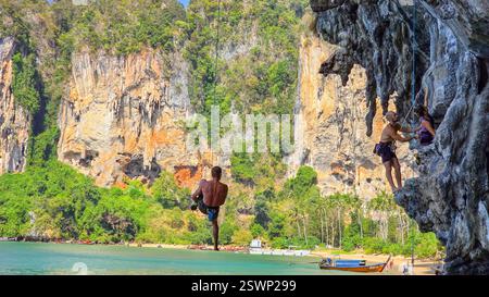 Krabi Thaïlande 31 janvier 2025, les aventuriers grimpeurs escaladent les superbes falaises calcaires le long de la plage de Railay. Les eaux turquoises créent une toile de fond à couper le souffle pour une journée d'escalade exaltante Banque D'Images