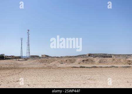 Deux tours de télécommunication s'élevant contre un ciel bleu clair dans le paysage désertique aride de marsa alam, en égypte, fusionnant technologie et nature Banque D'Images
