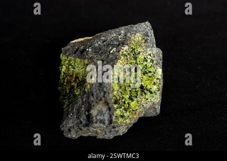 Un xénolithe de cristaux de péridot vert vif avec quelques cristaux d'Olivine foncés, en basalte Banque D'Images