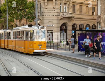 Budapest, Hongrie, 29 août 2022. Les gens à l'arrêt de tram. La locomotive d'époque de la ligne 47 arrive. Couleur jaune et blanche caractéristique. LIF Banque D'Images