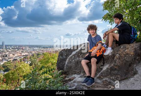 Budapest, Hongrie, 29 août 2022. Deux jeunes gens se reposent sur un rocher regardant le paysage urbain du haut de la colline. Belle journée d'été avec du bleu Banque D'Images