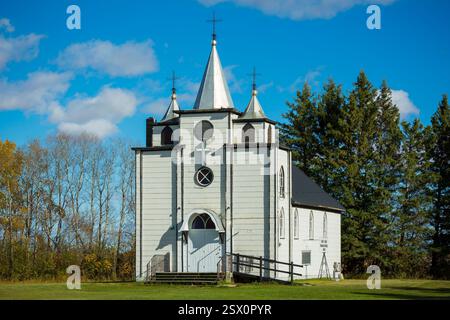 Église blanche avec un clocher et une croix sur le dessus. L'église est entourée d'arbres Banque D'Images