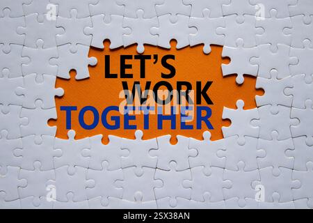 Travaillons ensemble symbole. Les mots conceptuels permettent de travailler ensemble sur le puzzle blanc. Beau fond orange Business and Lets Work Together concept. Copier Banque D'Images