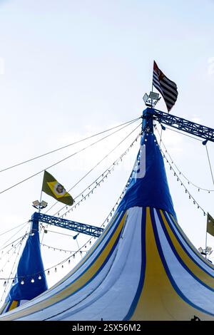 Tente de cirque motif rayé bleu, jaune et blanc avec drapeaux, sur le ciel bleu Banque D'Images