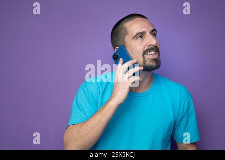 Heureux jeune homme parlant avec un téléphone portable sur fond de couleur Banque D'Images