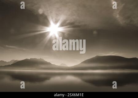 Photographie de paysage du lac Léman par une journée ensoleillée, lumière parasite, les montagnes qui se reflètent en elle dans le lac, teinte sépia, monochrome Banque D'Images