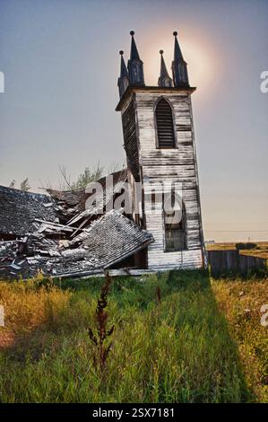 Clocher d'église avec un toit cassé et une fenêtre. L'église est vieille et abandonnée. Le soleil brille sur l'église, la faisant paraître encore plus désolée Banque D'Images