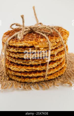 Une pile de gaufres belges au caramel fraîchement préparées nouées avec de la ficelle de jute se trouve sur une surface en toile de jute, célébrant la Journée nationale du caramel avec des saveurs riches et Banque D'Images