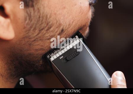 Gros plan d'un homme qui tond sa barbe avec une tondeuse électrique Banque D'Images