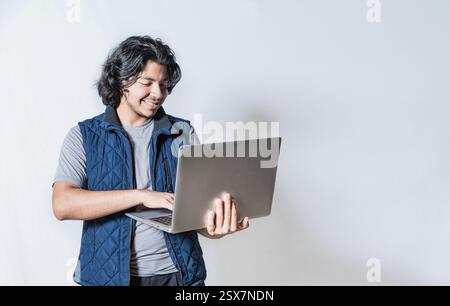 Sourire bel homme regardant une promotion sur ordinateur portable isolé. Heureux jeune homme utilisant un ordinateur portable isolé Banque D'Images