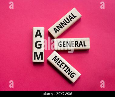 AGA - symbole de l'Assemblée générale annuelle. Mot concept AGM sur cubes en bois. Beau fond rouge. Business et AGM concept. Copier l'espace. Banque D'Images