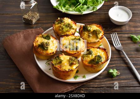 Muffins aux œufs chargés faits avec des œufs, du jambon, du brocoli, du fromage sur une table en bois brun. Repas savoureux pour le petit déjeuner ou le déjeuner. Vue rapprochée Banque D'Images