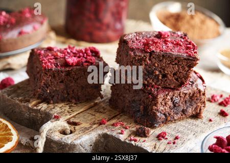 Trois morceaux de brownies sans gluten faits maison à base de haricots rouges, flocons d'avoine, chocolat et framboises lyophilisées sur une table en bois Banque D'Images