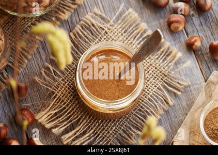 Beurre de noisette maison dans un pot en verre avec une cuillère, vue de dessus Banque D'Images