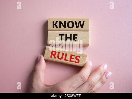 Connaître le symbole des règles. Les blocs de bois avec des mots connaissent les règles. Beau fond rose. Main d'homme d'affaires. Affaires et connaître le concept de règles. Copier Banque D'Images